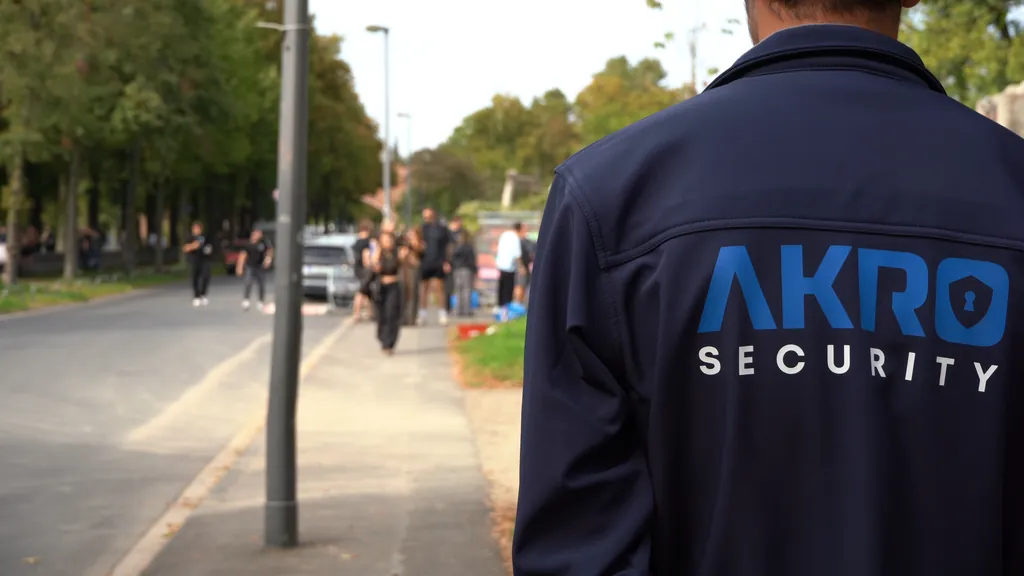 Mitarbeiter von AKRO Security in dunkelblauer Jacke mit AKRO-Logo, von hinten, bei einem Einsatz im Freien